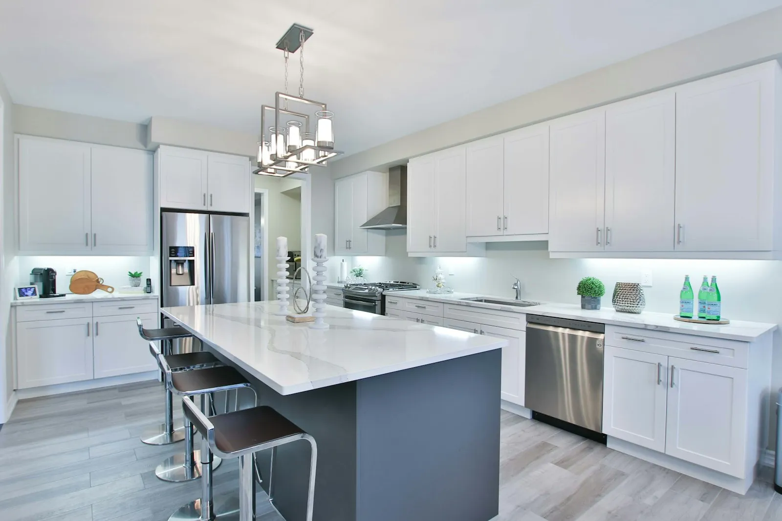 Cocina reformada con isla central, muebles blancos y encimera clara